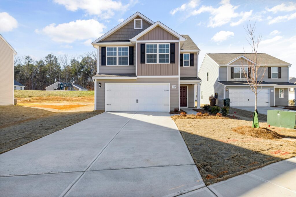 pexels-photo-10827225-10827225 Contemporary suburban house with a wide driveway and landscaped front yard.
