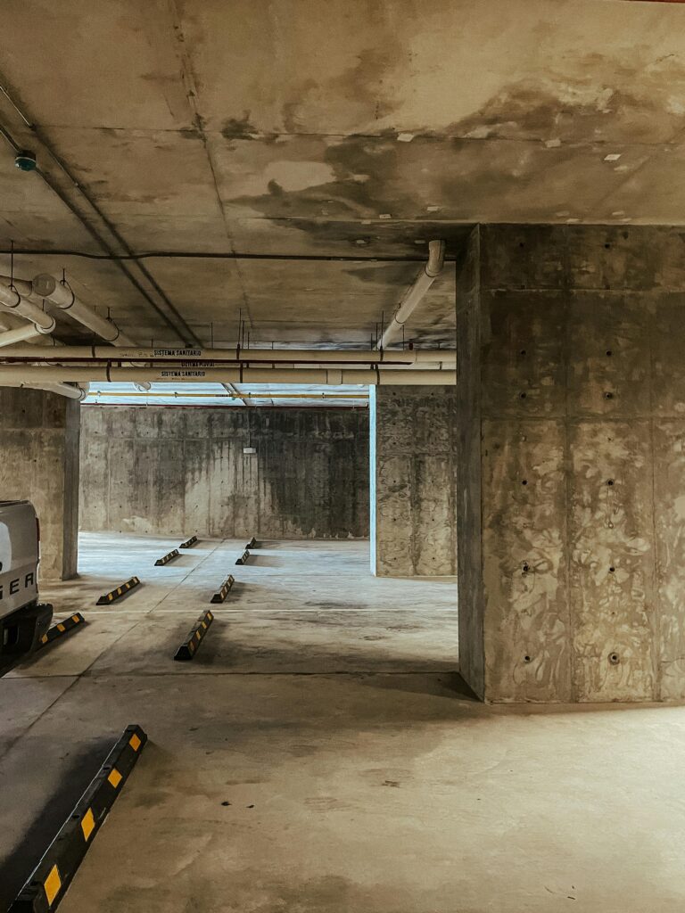 pexels-photo-14002092-14002092 A vacant indoor concrete underground parking garage with minimal vehicles and structural columns.
